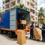Professional movers loading cardboard boxes into a moving truck, illustrating reliable relocation services in India.